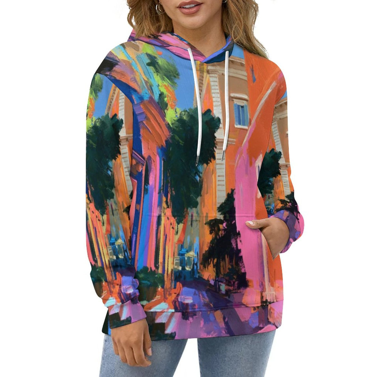A woman wearing a colorful pullover hoodie with an all-over abstract city street print in bright orange, pink, blue, green, and purple tones, paired with light blue jeans against a plain white background.
