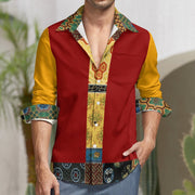A man wearing a long-sleeve button-up shirt with a bold color-blocked design. The shirt features a deep red body, mustard yellow sleeves, and a central panel and collar with a detailed geometric and tribal pattern in green, yellow, brown, and blue.