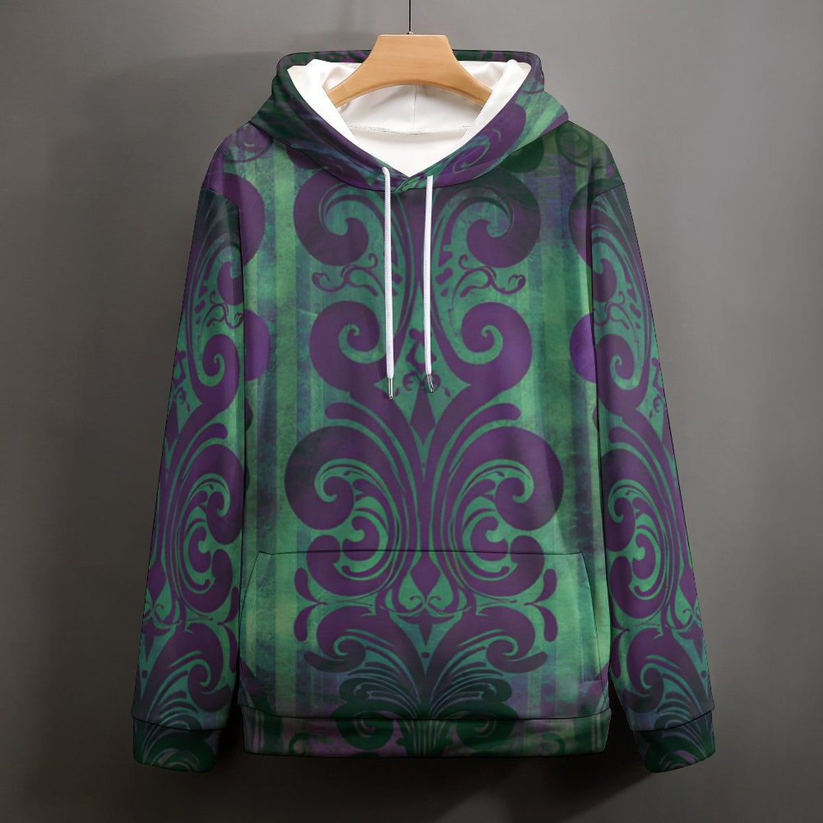 A pullover hoodie with a green and purple damask pattern, hanging on a wooden hanger against a dark gray background.