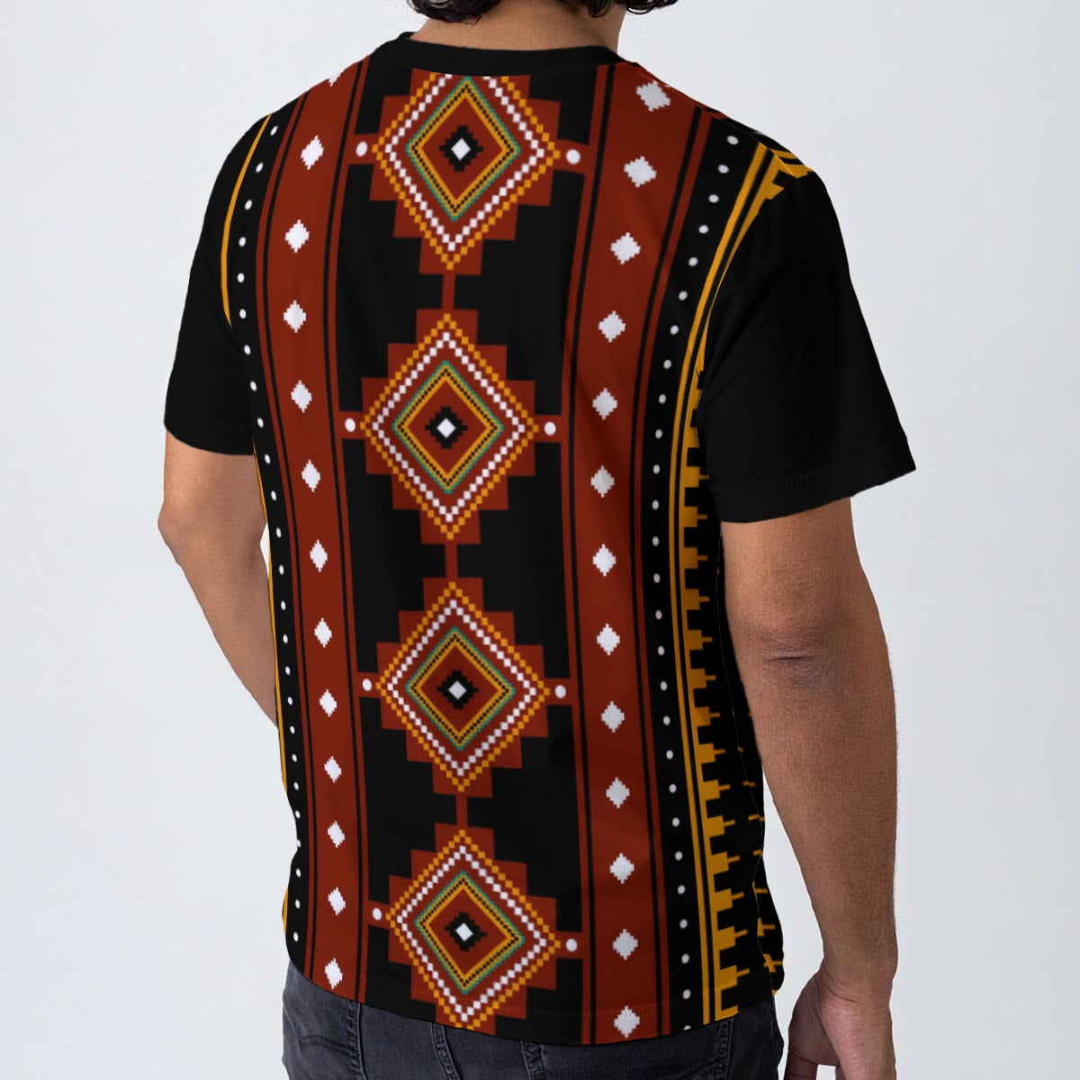 A man wearing a black short-sleeve t-shirt with a bold Southwestern geometric pattern on the back, featuring red, brown, yellow, and white diamond motifs, shown from a rear three-quarter view.