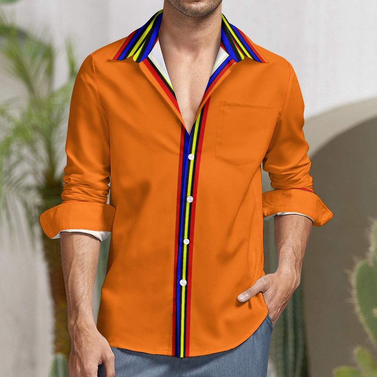 A man wearing a bright orange long-sleeve button-up shirt with a multicolor striped collar and front placket, paired with blue jeans.