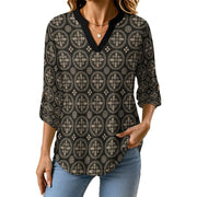 A woman wearing a black three-quarter sleeve blouse with a beige geometric circular pattern and a V-neckline, paired with light blue jeans against a plain white background.