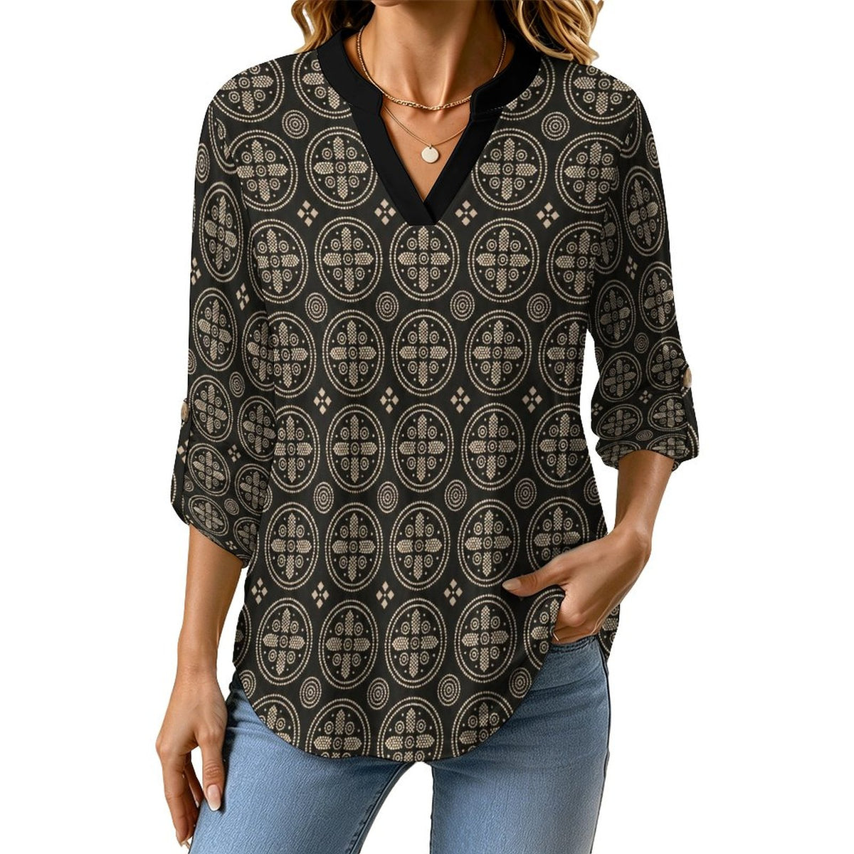 A woman wearing a black three-quarter sleeve blouse with a beige geometric circular pattern and a V-neckline, paired with light blue jeans against a plain white background.