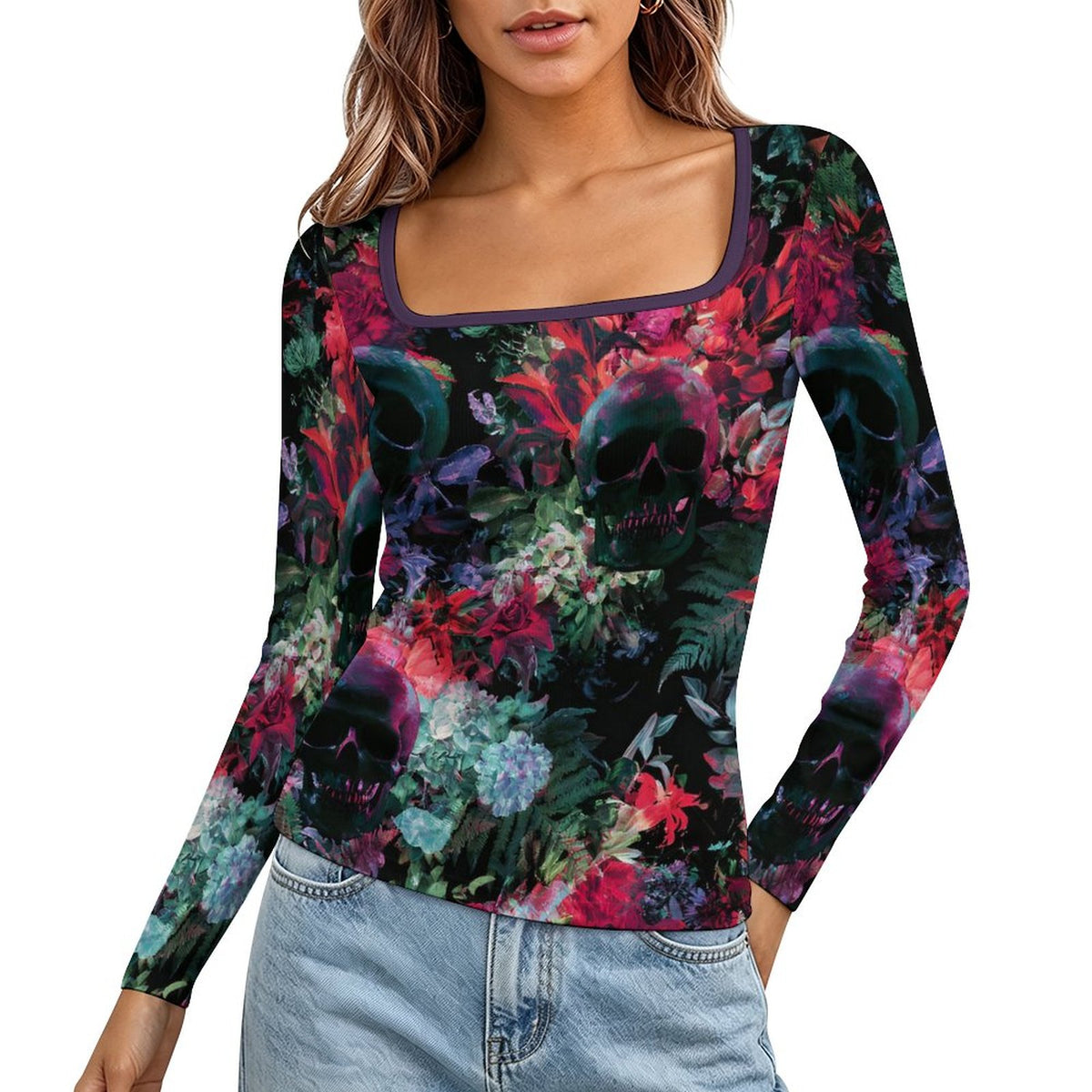 A woman wearing a long-sleeve scoop-neck top with a vibrant gothic floral and skull print, paired with light-wash blue jeans, shown against a plain white background.